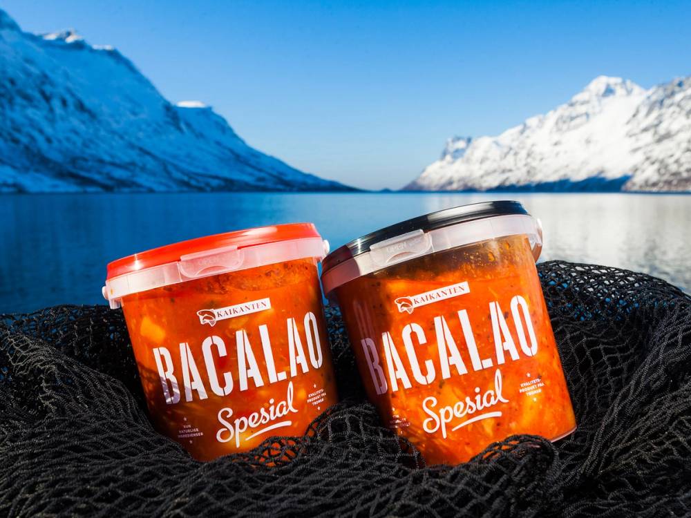 To beholdere med Bacalao Spesial på en svart overflate foran et snødekt fjellandskap og en klar blå himmel.