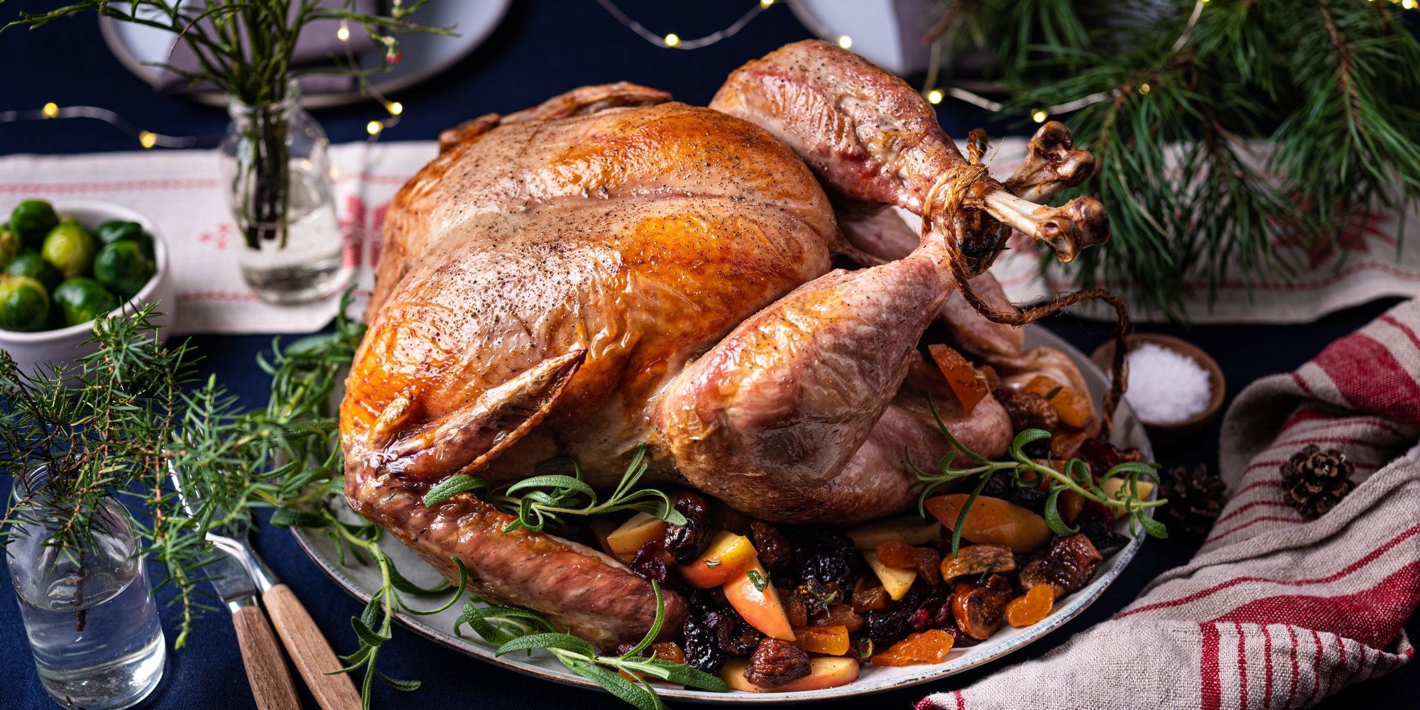 En stekt kalkun på et serveringsfat med grønnsaker og urter rundt, klar til å bli servert.