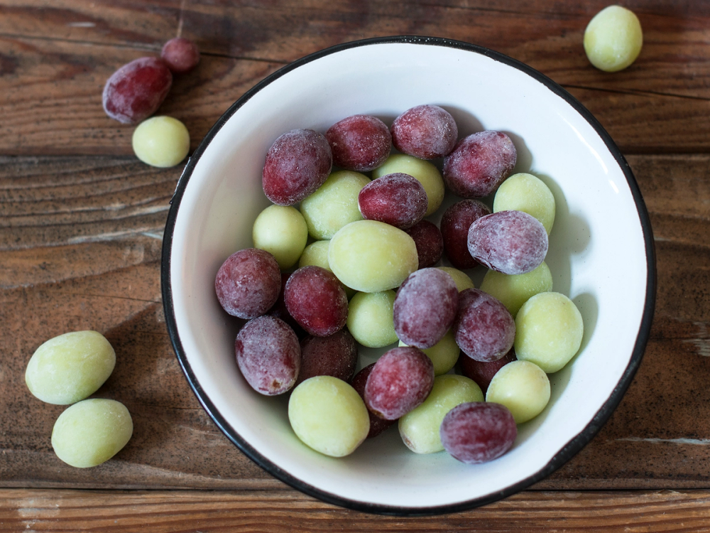 Frosne druer i en skål på et trebord