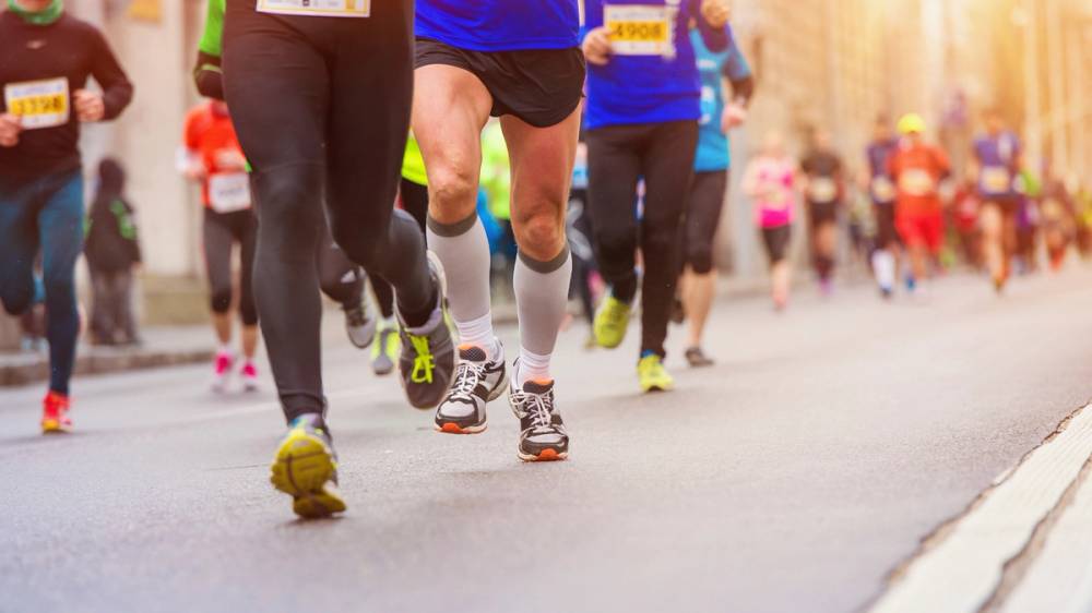 Løpere i ulike farger på vei under Oslo-maraton 2016, sett fra bakkenivå med fokus på føttene og beina deres.