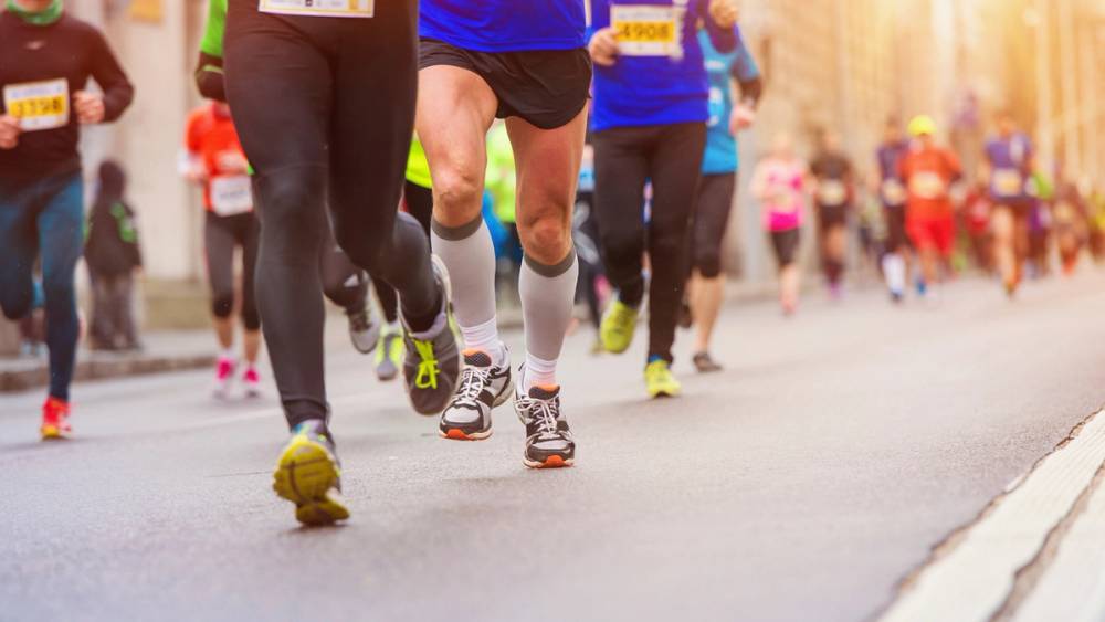 Løpere i ulike farger på vei under Oslo-maraton 2016, sett fra bakkenivå med fokus på føttene og beina deres.