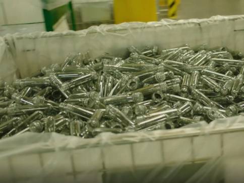 Mange tomme PET-flasker ligger i en stor plastkasse før fylling.