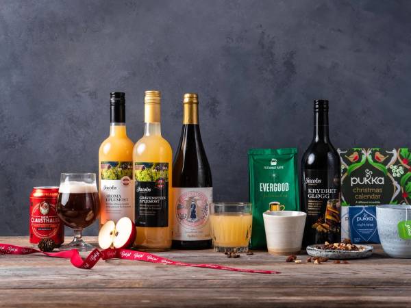 Ulike juledrikker og tilbehør på et bord, inkludert vin, øl, juice, og julepynt.