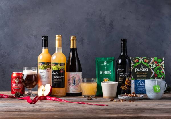 Ulike juledrikker og tilbehør på et bord, inkludert vin, øl, juice, og julepynt.