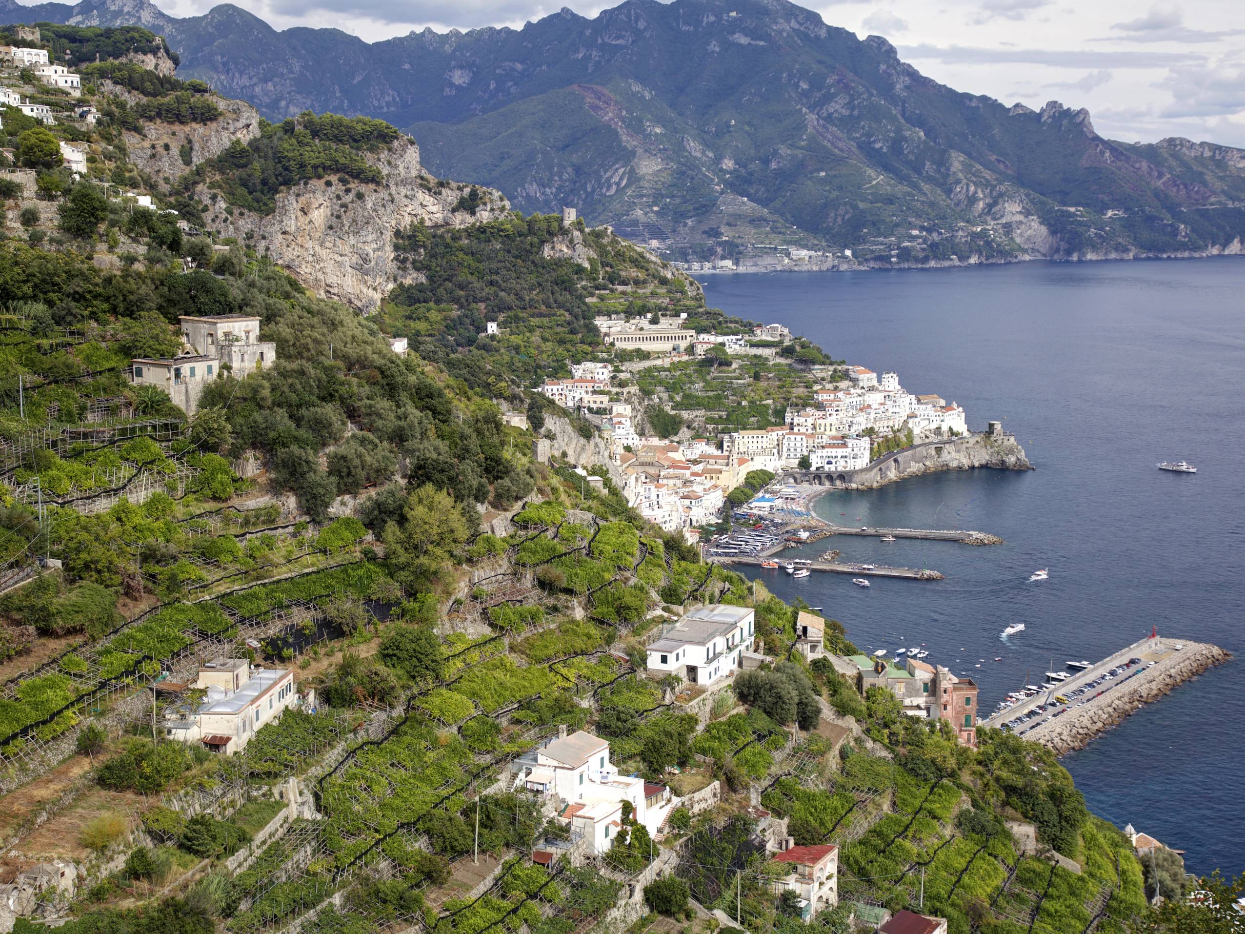 Skråning med hvite hus og grønne terrasser som strekker seg ned mot sjøen på Amalfikysten.