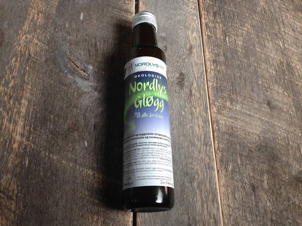 En flaske med Nordlysglögg står på et treverk, med etiketten tydelig synlig.