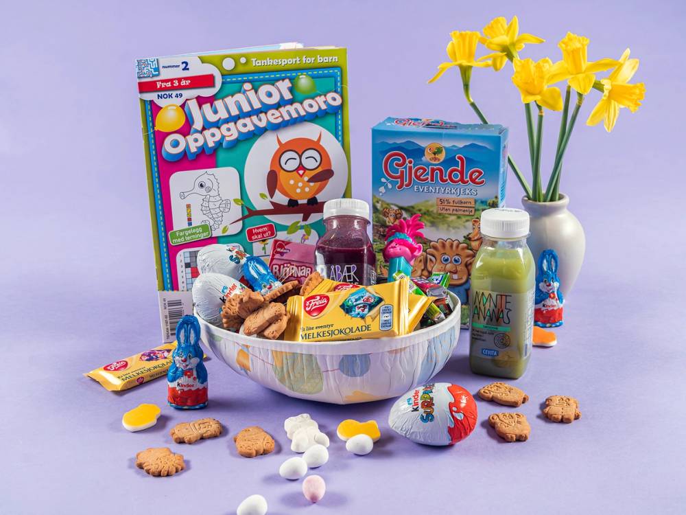 Påskeegg og godteri i en skål med blomster i bakgrunnen, klare til å deles ut til barn.