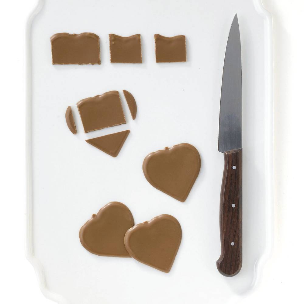 Ulike former av sjokolade på et hvitt brett med en kniv ved siden av.