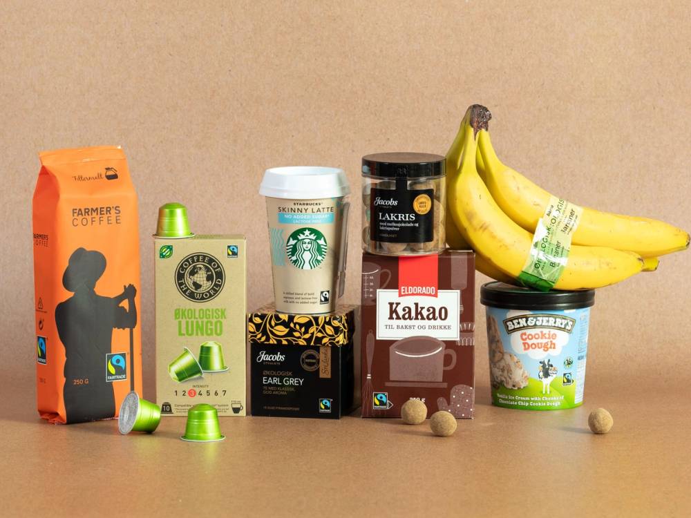 En gruppe Fairtrade-merkede produkter, inkludert kaffe, te, sjokolade og bananer, plassert på en beige bakgrunn.