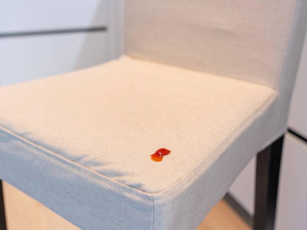 En liten rød og svart ladybug på en lysfarget stolseteflate.