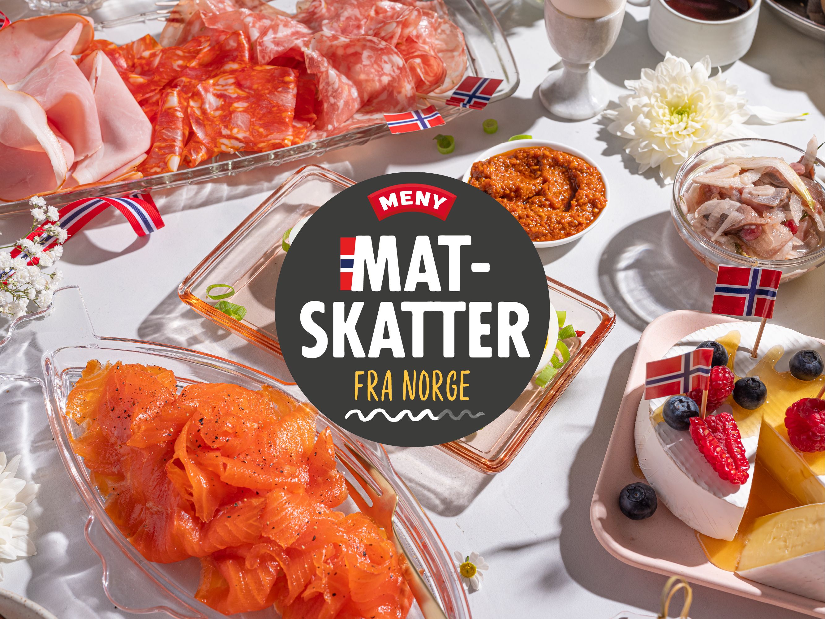 Ulike typer av mat, inkludert røkt laks, kjøtt og en kake med bær, på et bord med norske flagg og en logo som sier 'Mat- skatter fra Norge'.