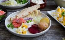 Tradisjonell rakfisk servert med tilbehør som poteter, grønnsaker og flatbrød på et fat.