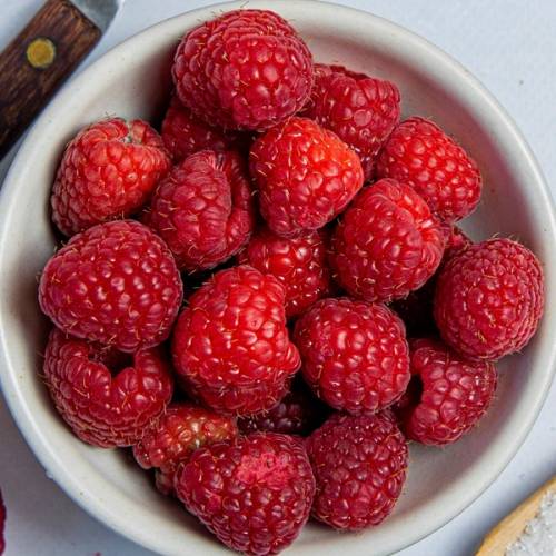 En skål med friske bringebær, klare og røde, klare til å brukes i syltetøy eller som snacks.