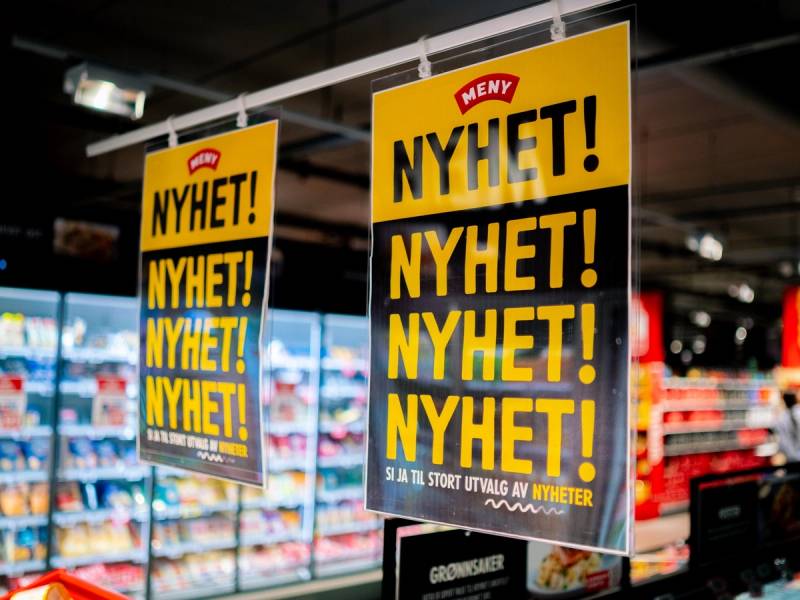 To plakater med teksten 'NYHET! NYHET! NYHET!' henger i en butikk, med MENY-logo øverst.