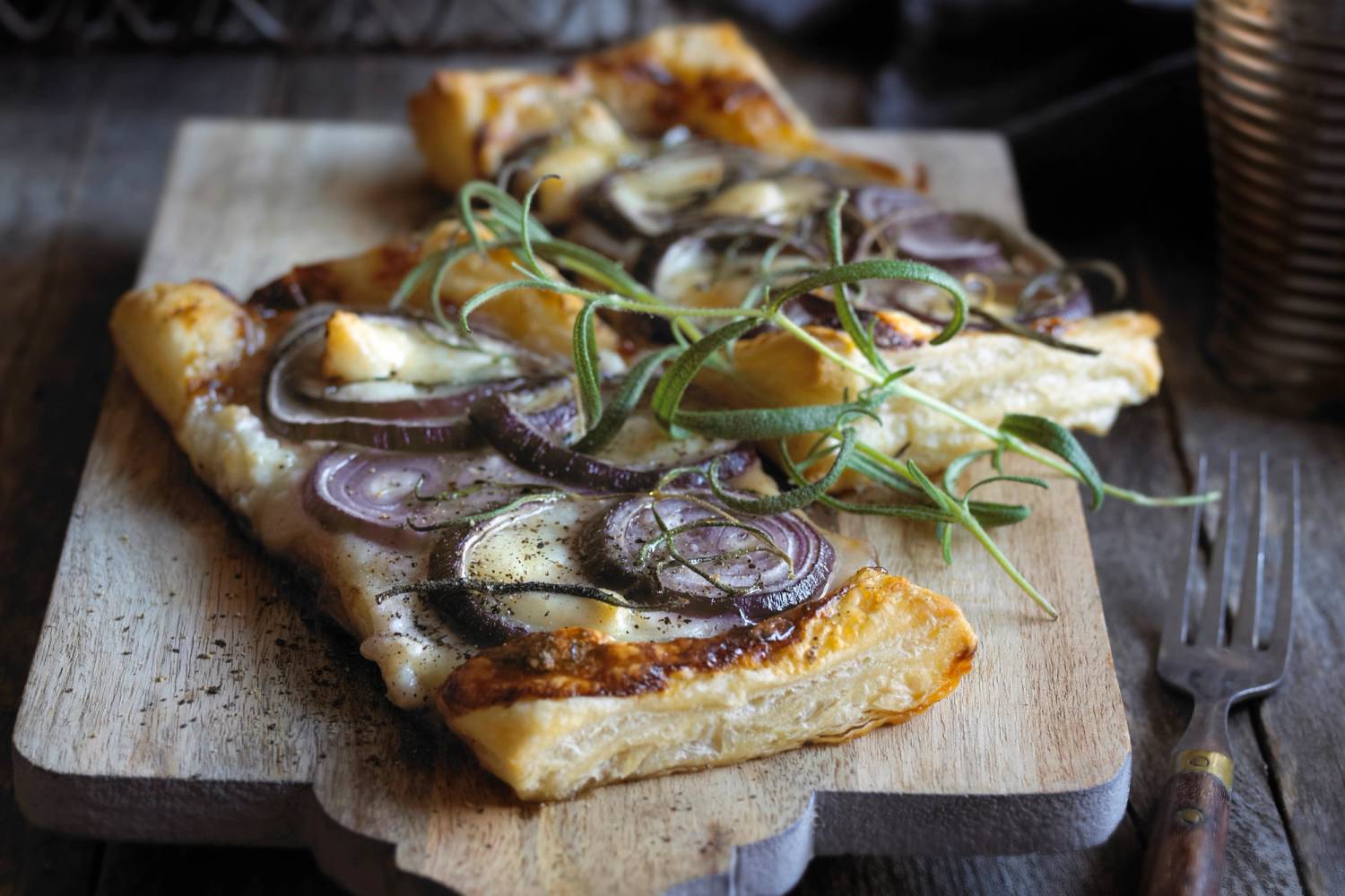 En pizza med sopp, løk og grønne urter på en treplate, klar til å serveres.