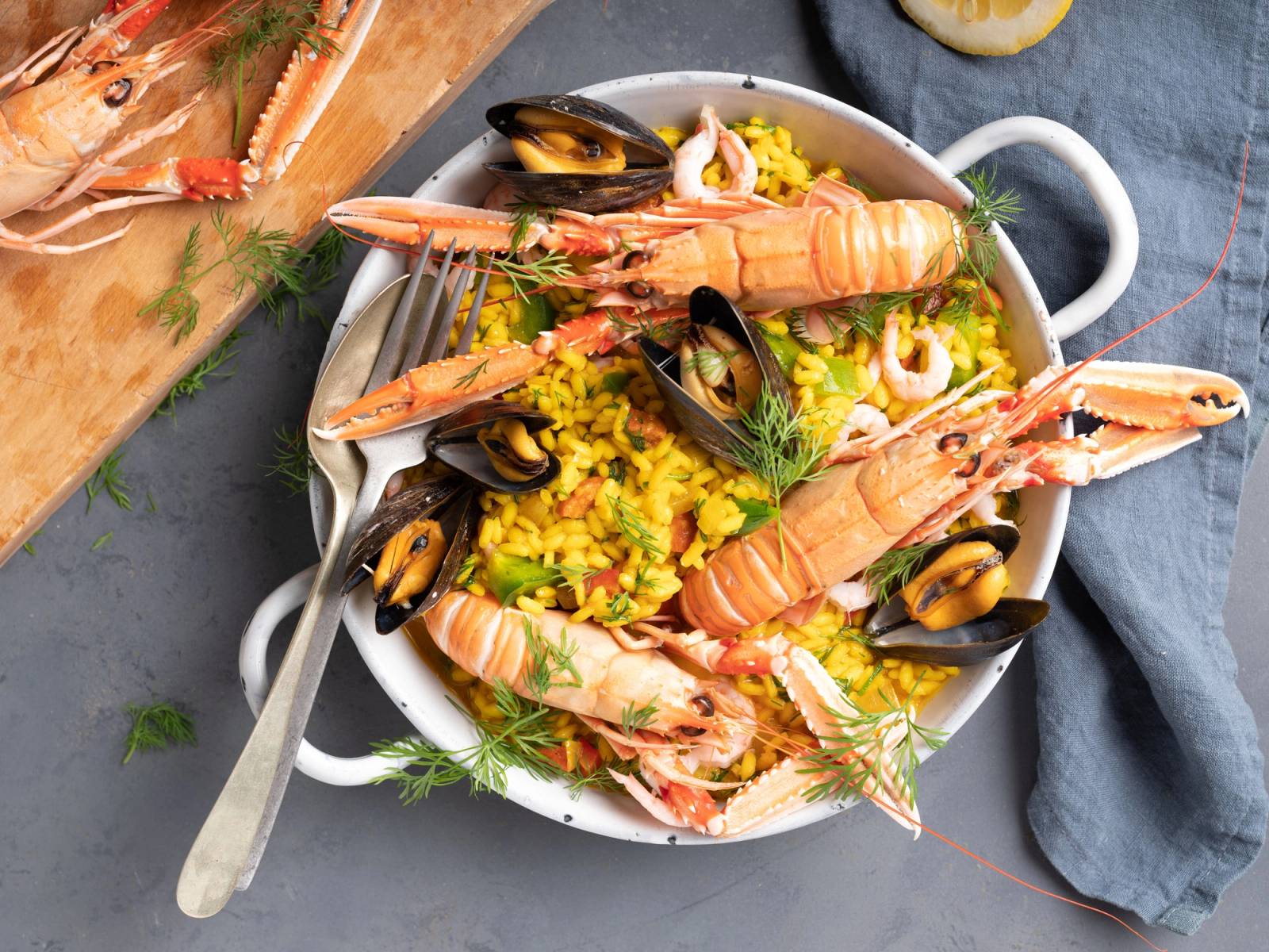 Paella med reker, blåskjell og sitron på en hvit tallerken sett ovenfra.