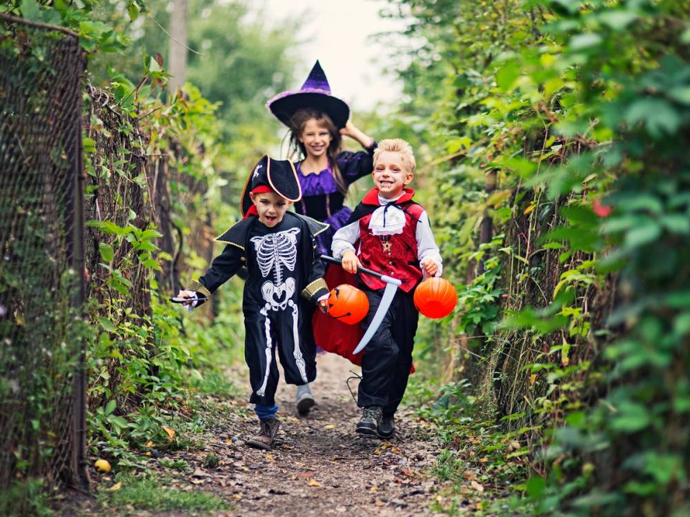 Barn kledd ut i skumle kostymer med blodig popcorn, gående langs en skogssti.