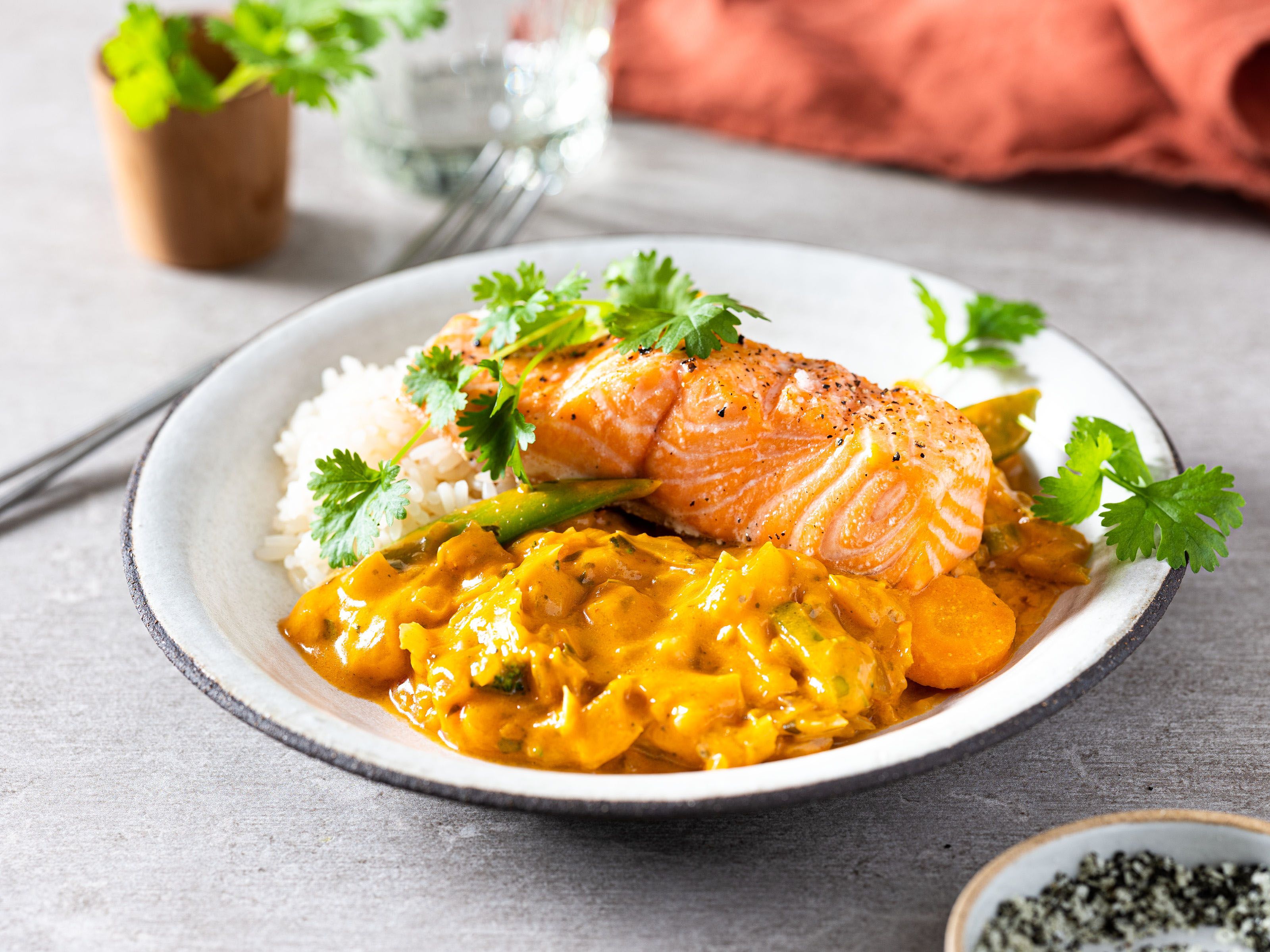 Stekt ørret med rød curry og grønne urter på en hvit tallerken