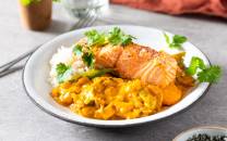 Stekt ørret med rød curry og grønne urter på en hvit tallerken