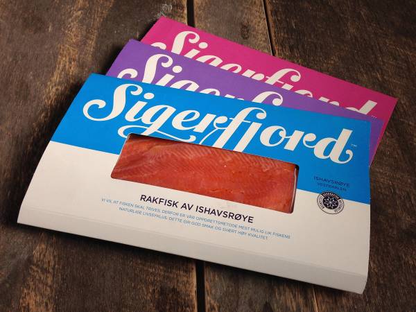 Pakke med Sigerfjord-merkede lakseprodukter på en treoverflate, med tydelig Sigerfjord-logo og tekst om råfisk av ishavsrøye.