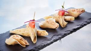 Små tapas med skinke og grønnsaker på en svart steinplate