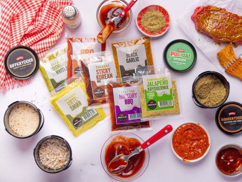 Ulike marinader og sauser i små beholdere og pakninger på et hvitt bord med en rød og hvit sjalett i bakgrunnen.