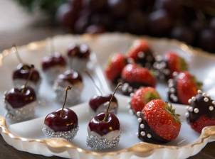 Nyttårsbordet med små kaker og fruktdekorasjoner, blant annet jordbær og kirsebær, pyntet med sølvkuler og sjokoladetrekk.