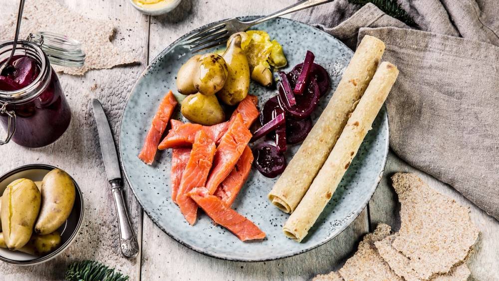 En tallerken med ulike typer sylte, inkludert grønne og røde varianter, samt to tynne flatbrød eller kjeks, plassert på et tre- eller steinbord.
