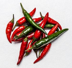 En gruppe med røde og grønne chilipepper på en hvit bakgrunn.