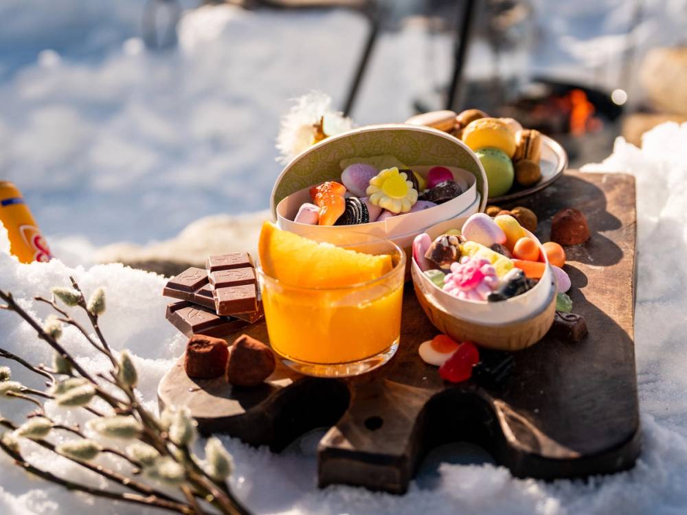 Påskegodt og sjokolade på et trebrett med snø i bakgrunnen