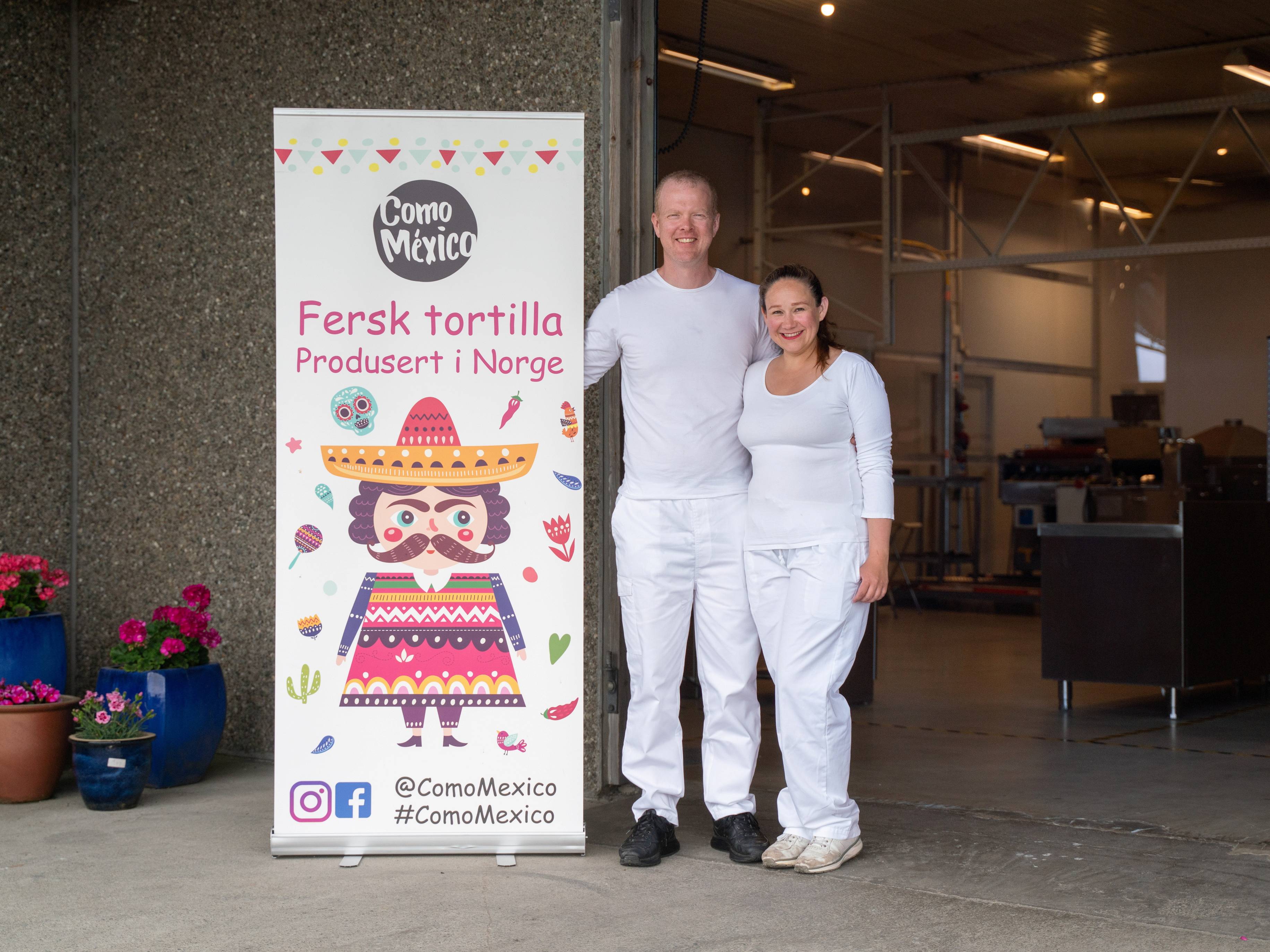 To personer står ved siden av en reklameskilt for Como Mexico med teksten 'Fersk tortilla' i en innendørs setting.