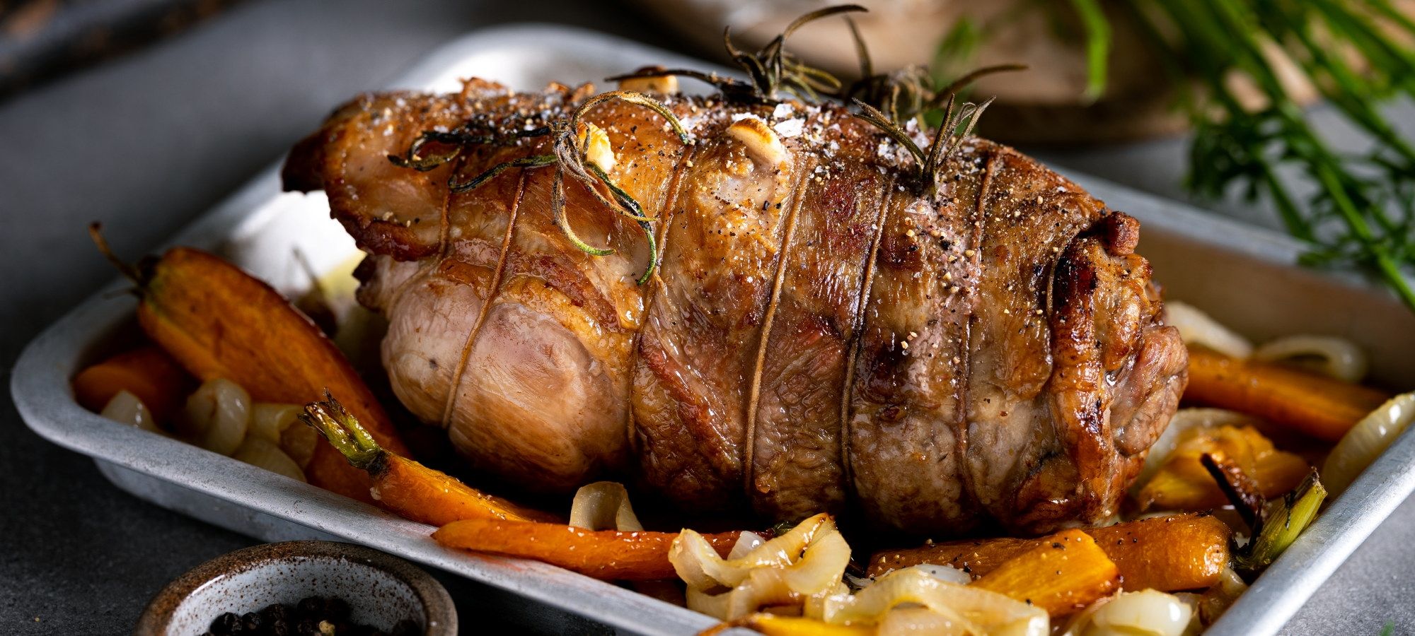 En klassisk lammestek servert på et fat med rotgrønnsaker og urter.