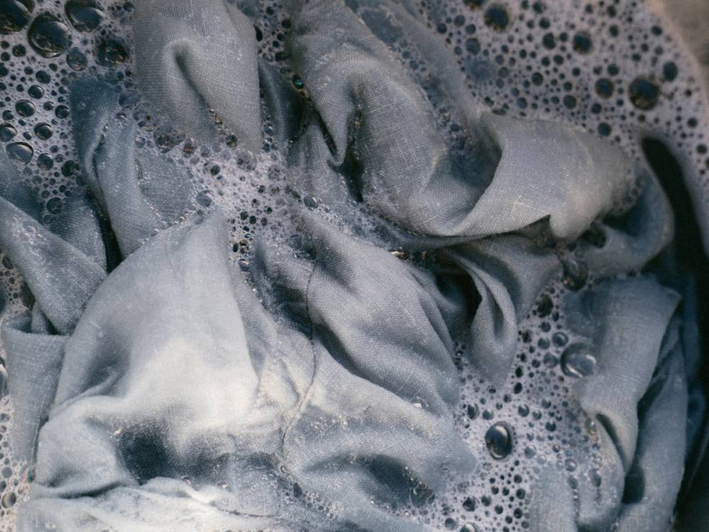 En klut eller håndkle som er vasket eller vasket opp i vann med såpe, med bobler og skum rundt.