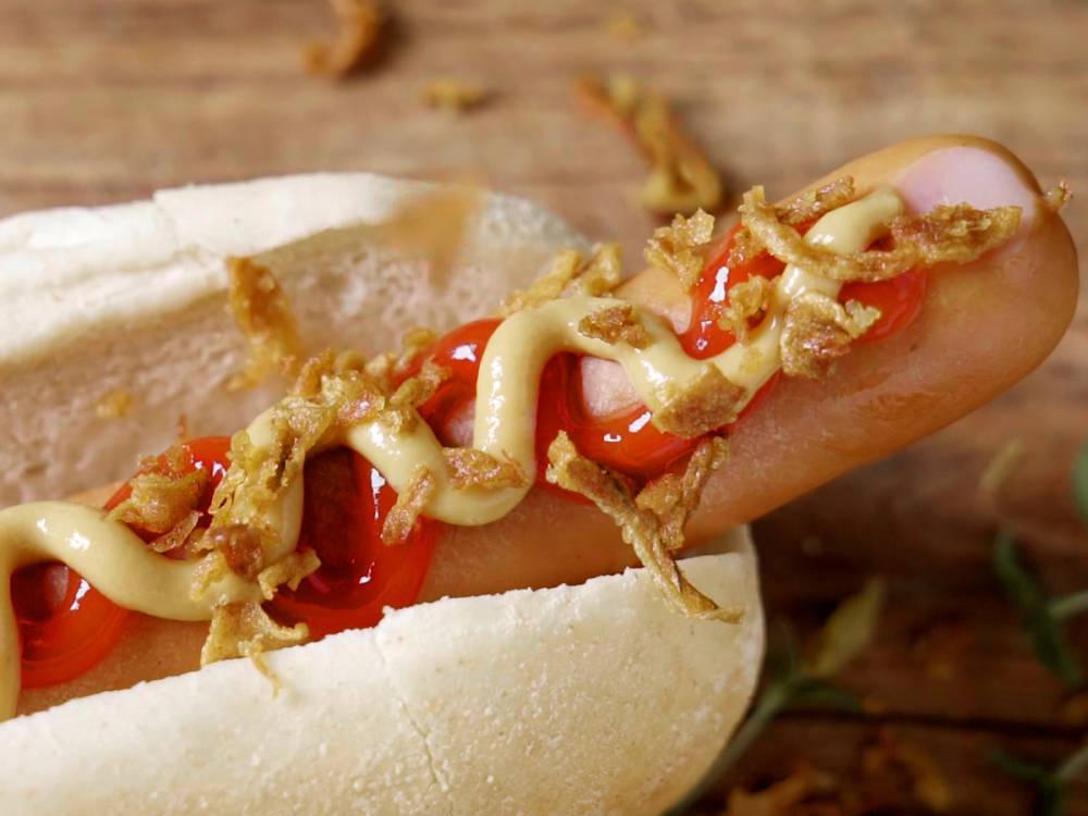 En pølse i et hvitt brød med ketchup og sennep, klar til å spises.