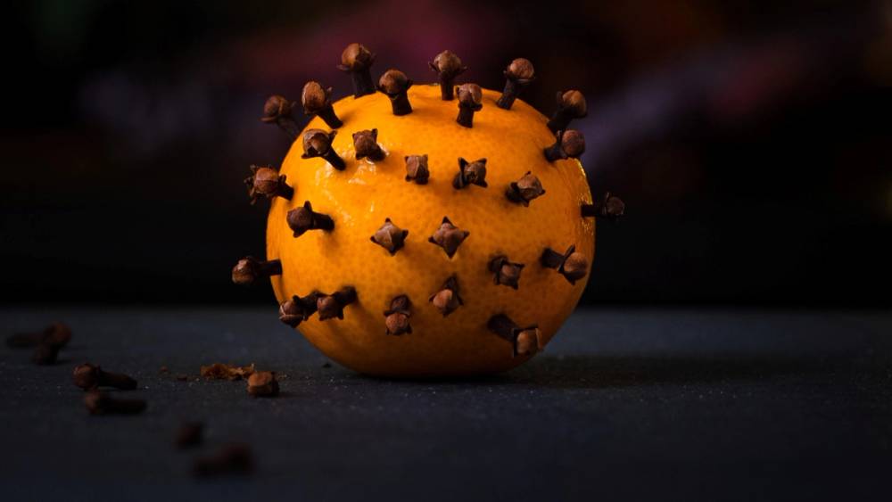 En coronaklementin med flere nellikspiker satt inn i skallet, plassert på en mørk bakgrunn.