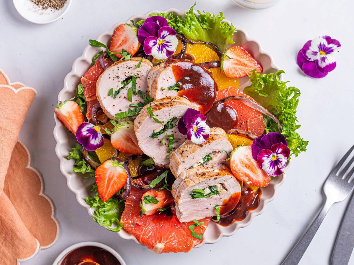Svinefilet fylt med ost og spinat, servert med en salat av jordbær, appelsinbiter og grønn salat, pyntet med spiselige blomster.