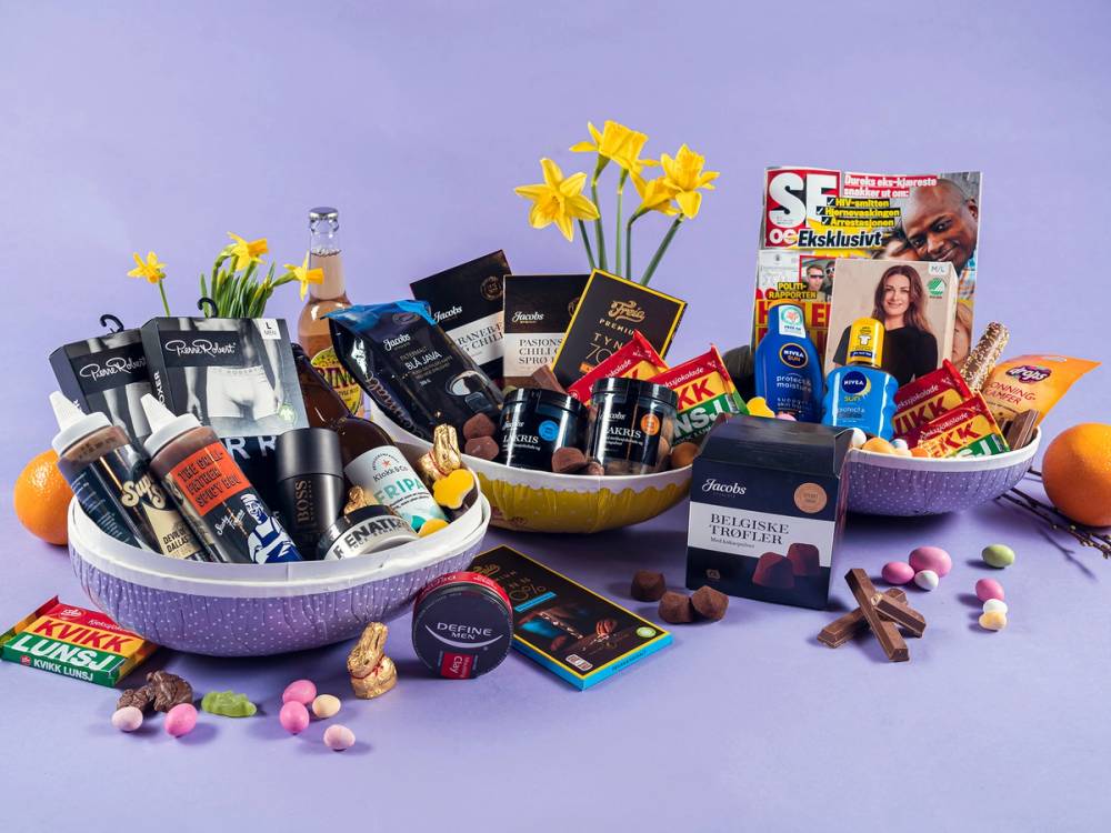 Et utvalg av påskeegg, sjokolade, gaver og blomster er arrangert på et bord, klar for påskefeiring.