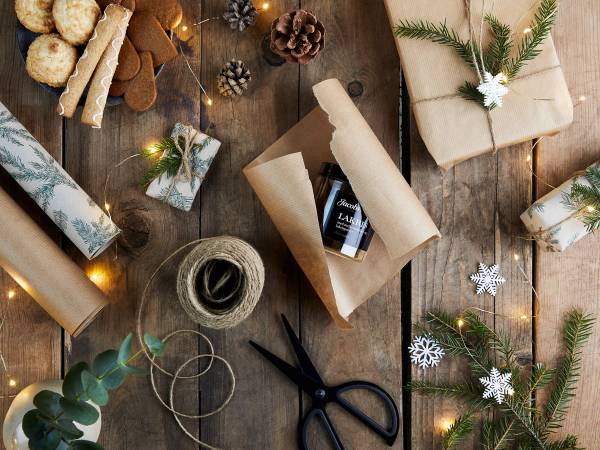 Julegaver, innpakningspapir, snøfnugg og pynt til julegaver på et bord.