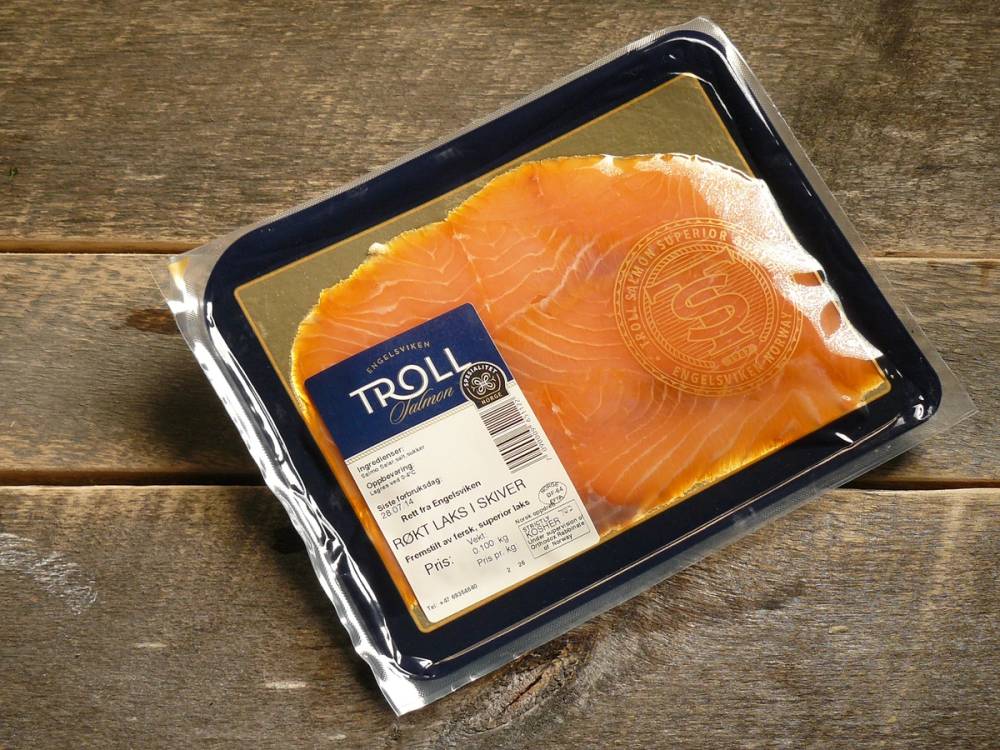 Pakke med laksefilet på en trebenk, med en etikett som viser at det er laks fra Troll.