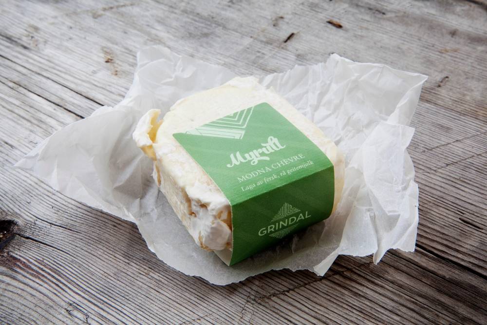 En myrull med hvit ost og grønn etikett ligger på et stykke papir på en treoverflate.