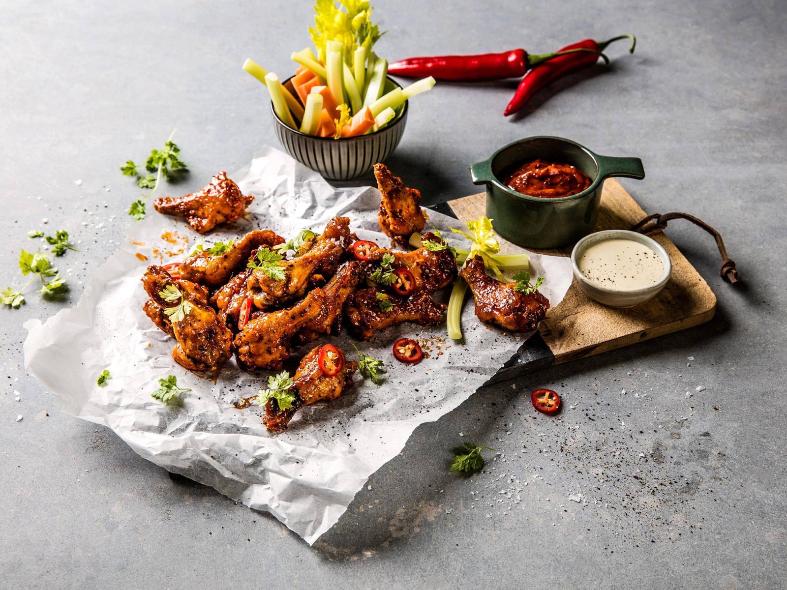 Buffalo wings med chili og grønnsaker på et fat med saus og dipper, klar for rask sommermat.