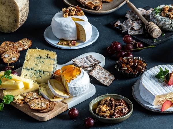 Et utvalg av ulike oster, kjeks, frukt og sjokolade på et bord, klar for helgekos.