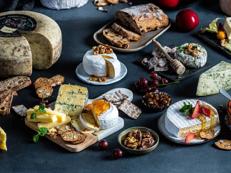 Et utvalg av ulike oster, kjeks, frukt og sjokolade på et bord, klar for helgekos.