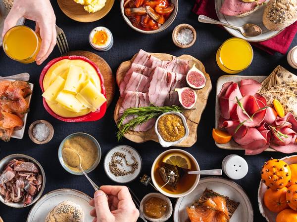 Et julefrokostbord med ulike retter, pølser, pålegg, egg, og frukt, sett fra oven.