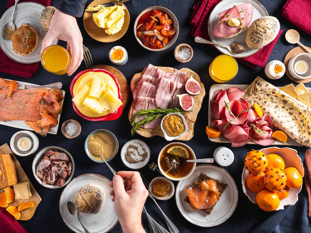 Et julefrokostbord med ulike retter, pølser, pålegg, egg, og frukt, sett fra oven.