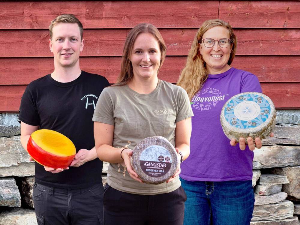 Tre personer holder ostekaker foran en rød vegg, med ansiktene dekket til.