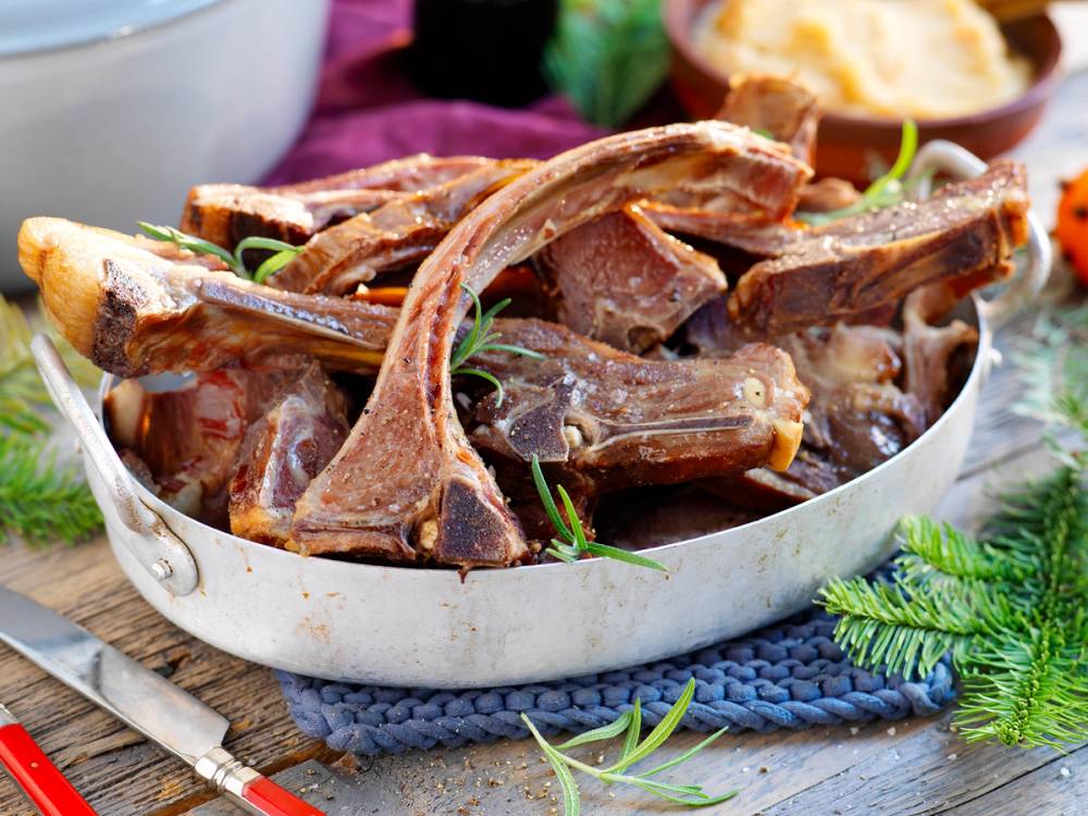 Pinnekjøtt med kokte poteter og grønnsaker på et fat.