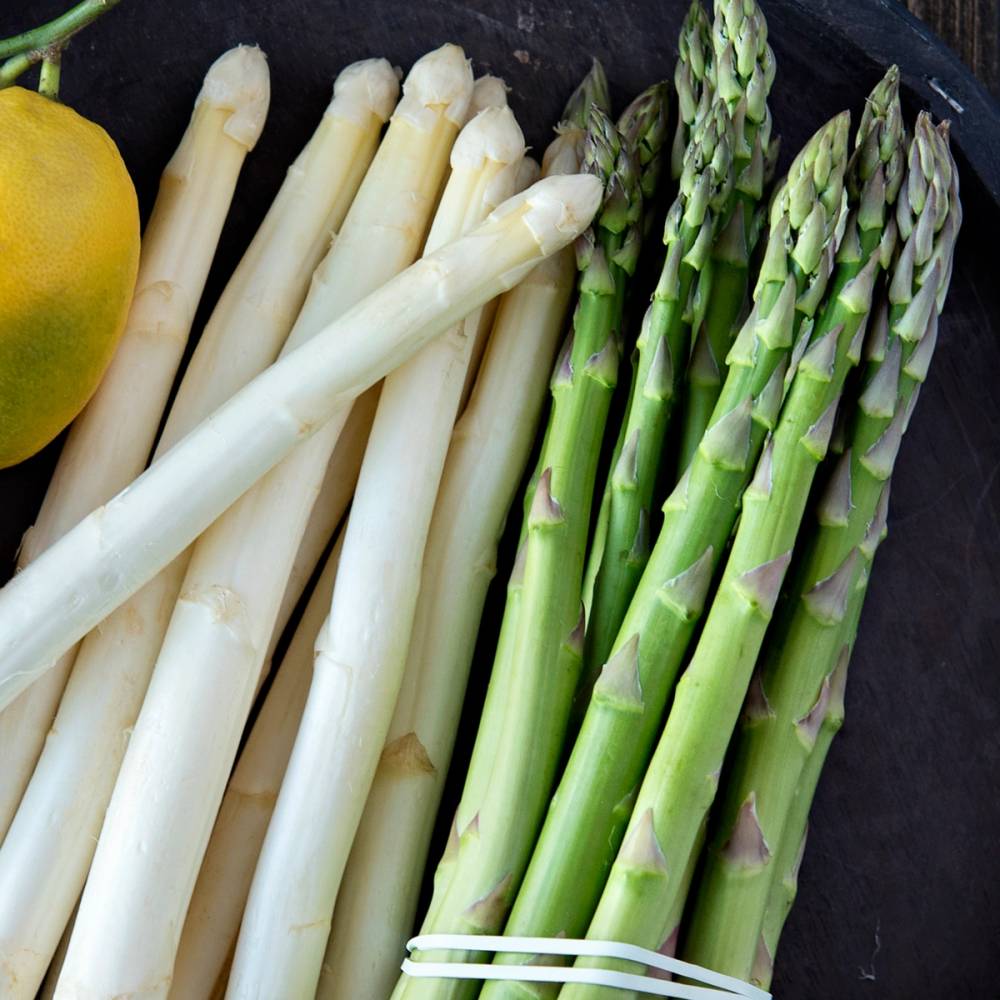 Hvit og grønne asparges ligger på en svart overflate.