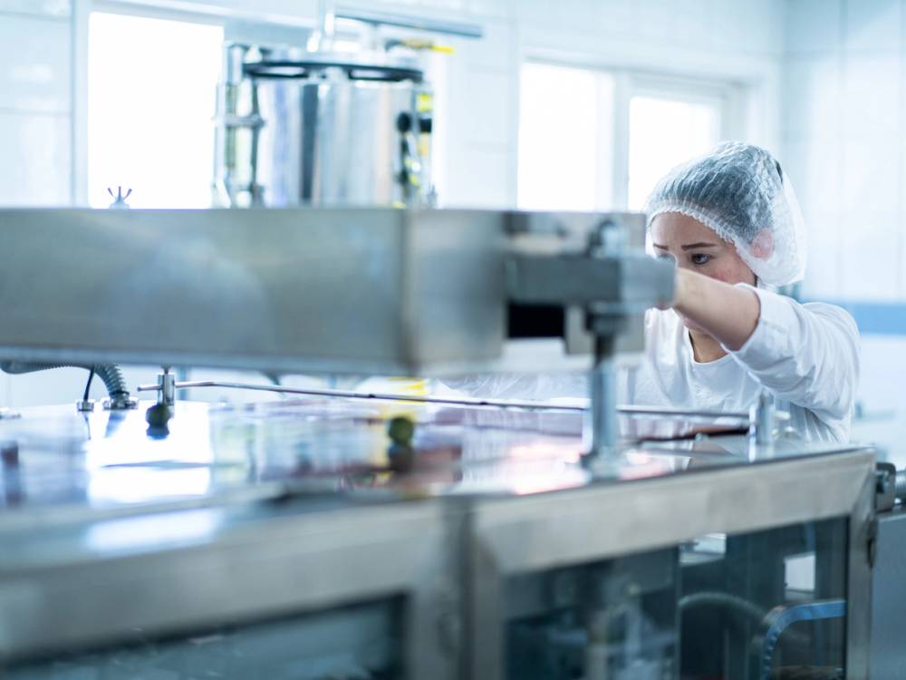 En person som jobber i en tortilla-produksjonsfabrikk, med maskiner og utstyr rundt seg.