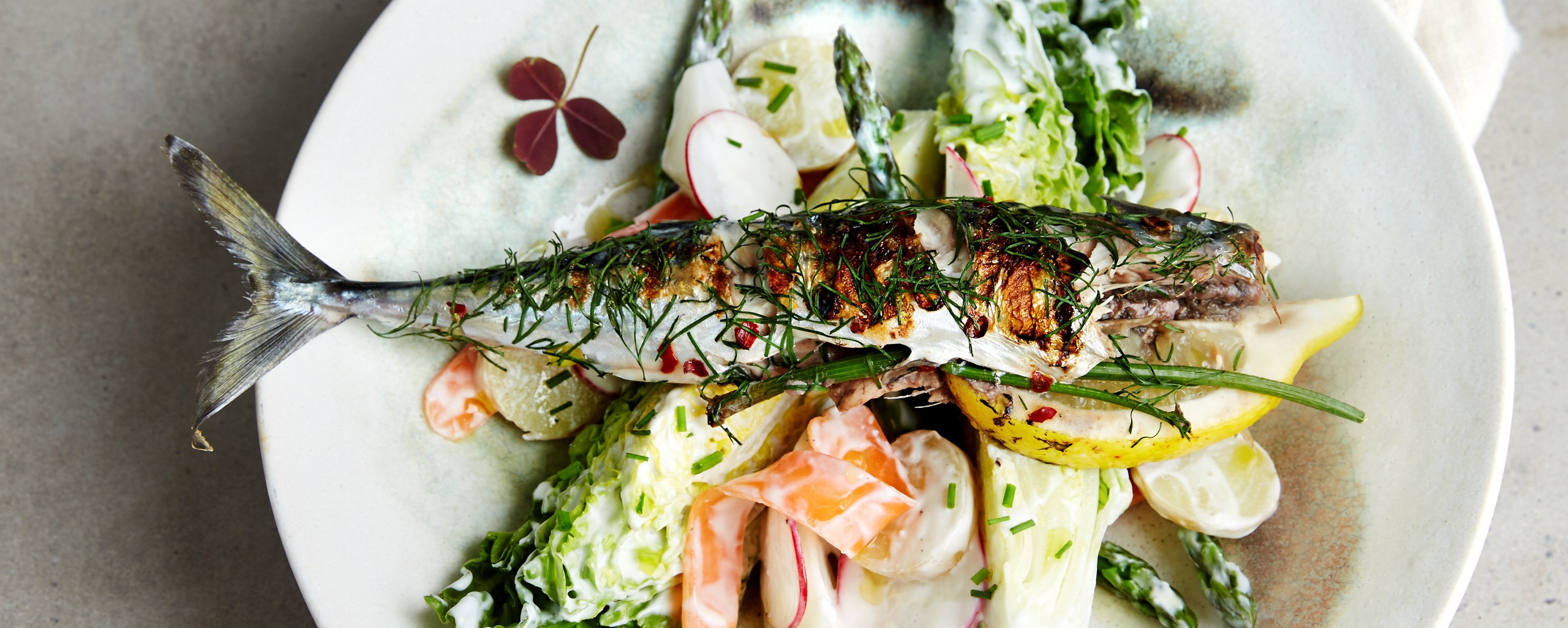 Grillet makrell med sitron og grønnsaker på en tallerken.